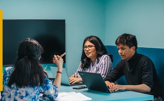 Students discuss their work in a meeting space